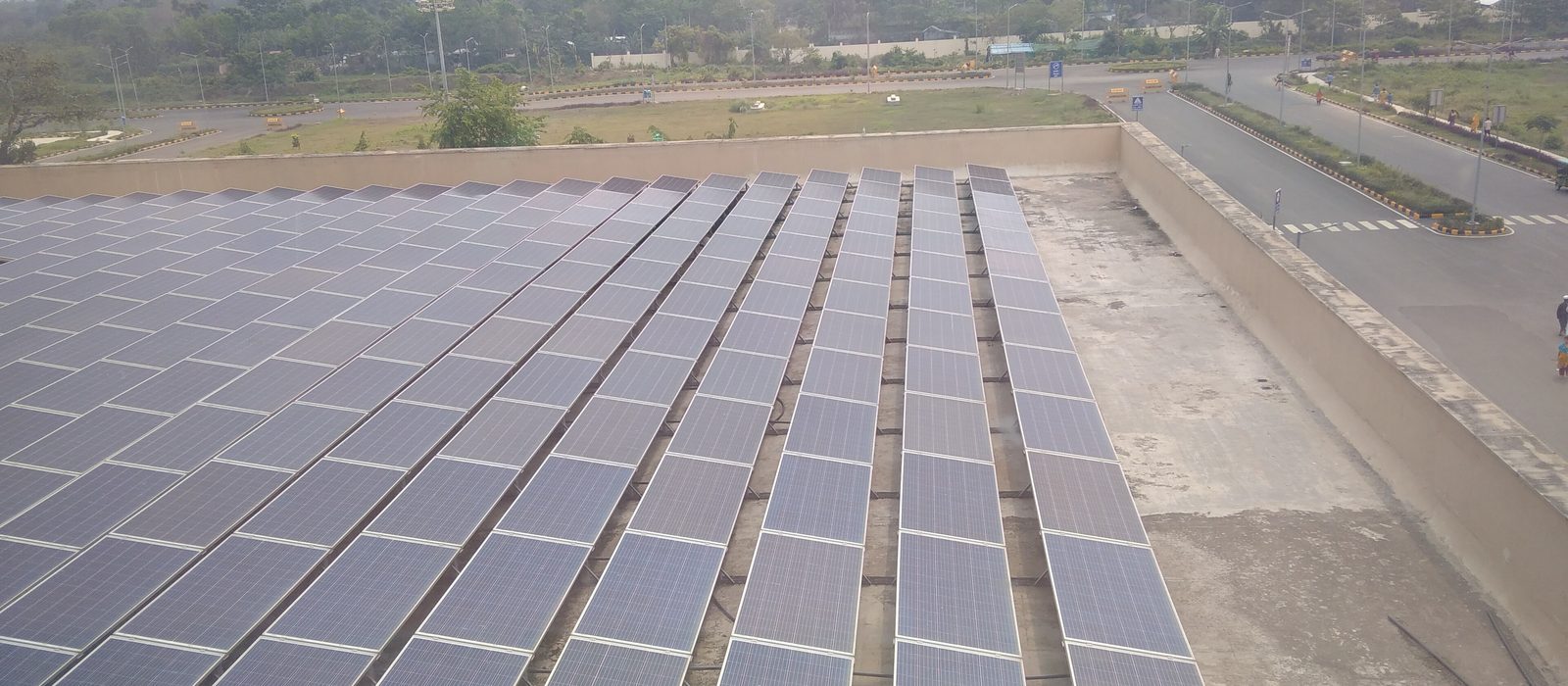 Rows of solar panels on a large flat concrete roof in India